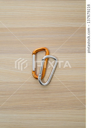Two-colored carabiners linked together and a wood grain background Two-colored carabiners linked together and a wood grain background 137679216
