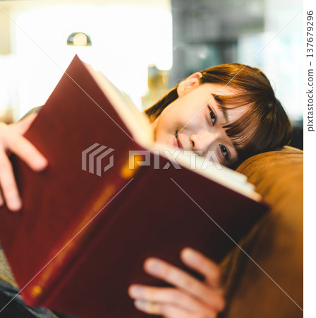 The face of a woman reading a book on a sofa 137679296