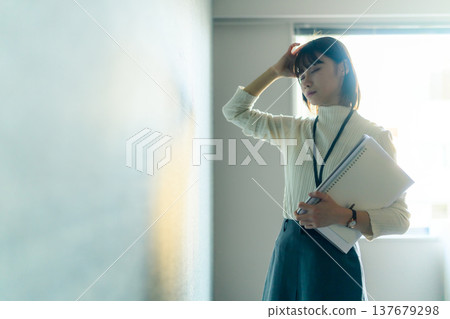 A female employee holds her head in her hands, exhausted (Cinematic photo) A female employee holds her head in her hands, exhausted (Cinematic photo) 137679298