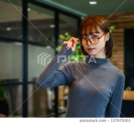 A woman wearing glasses looks at me. 137679301