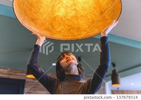 一名女子抬起一盞燈具。 137679314