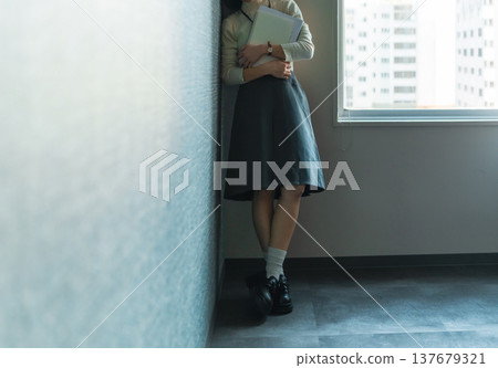 A female office worker stands motionless against the wall (Cinematic photo) A female office worker stands motionless against the wall (Cinematic photo) 137679321