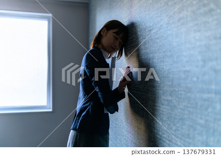 一位身穿西裝的女子倚牆而立，神情憂慮。 （電影劇照） 137679331