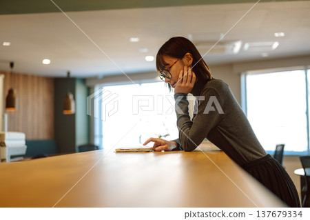 櫃檯上，一名女子正在操作平板電腦。 137679334