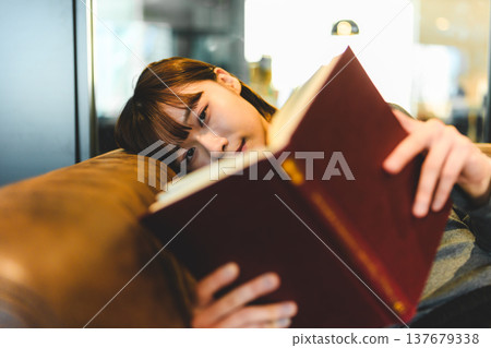 A woman picking up a book and looking at me. 137679338