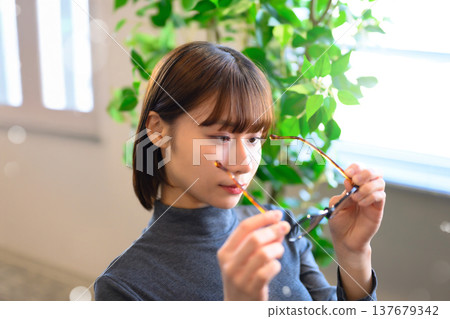 一位年輕女子檢查了一下手中的眼鏡。 137679342