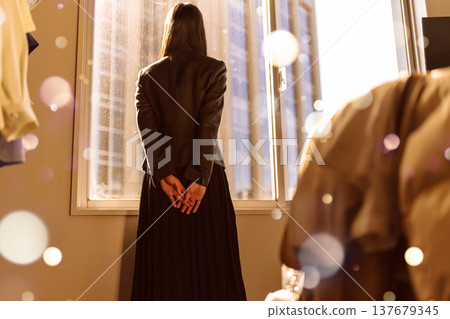 The back view of a woman standing by a window 137679345