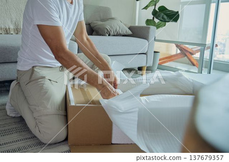 Man unpacking cardboard box with new furniture delivery Man unpacking cardboard box with new furniture delivery 137679357