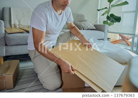 Man assembling diy furniture pieces in living room 137679363