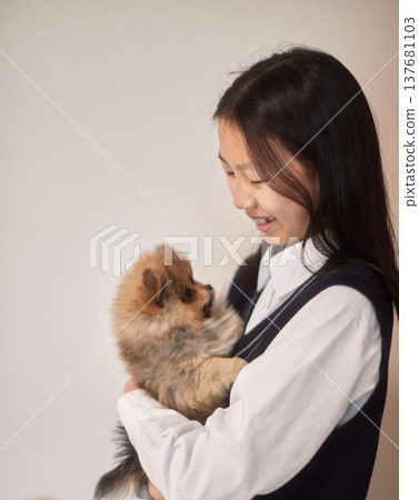 A middle school girl playing with a puppy in her living room. 137681103