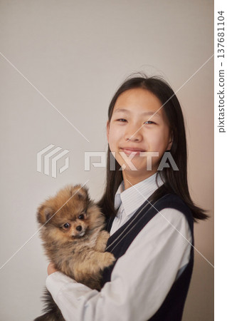 A middle school girl playing with a puppy in her living room. 137681104