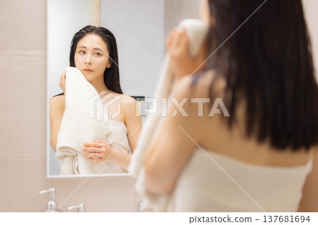 A woman checking her skin in the bathroom. A woman checking her skin in the bathroom. 137681694