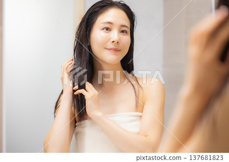 A woman doing hair care in the bathroom. 137681823