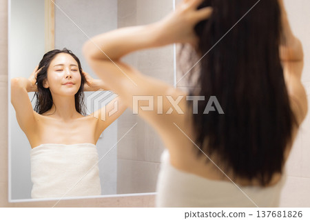 A woman doing hair care in the bathroom. A woman doing hair care in the bathroom. 137681826