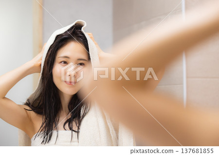 A woman doing hair care in the bathroom. A woman doing hair care in the bathroom. 137681855
