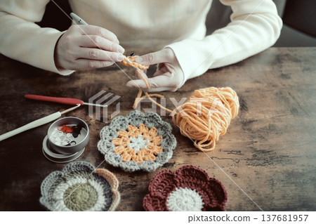 一位婦女的雙手和她用羊毛編織的作品 一位婦女的雙手和她用羊毛編織的作品 137681957