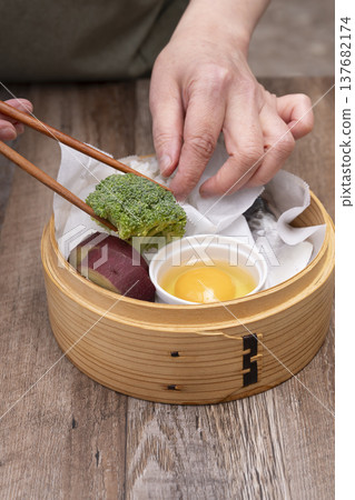 Prepare to make steamed breakfast in the kitchen using a bamboo steamer. 137682174