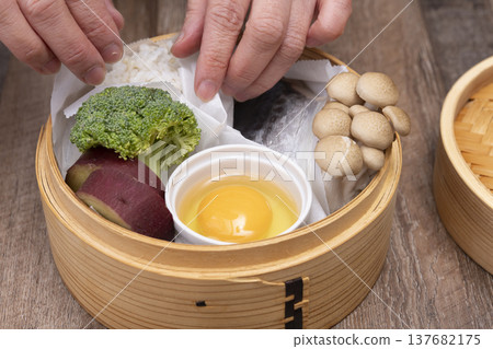 Prepare to make steamed breakfast in the kitchen using a bamboo steamer. 137682175