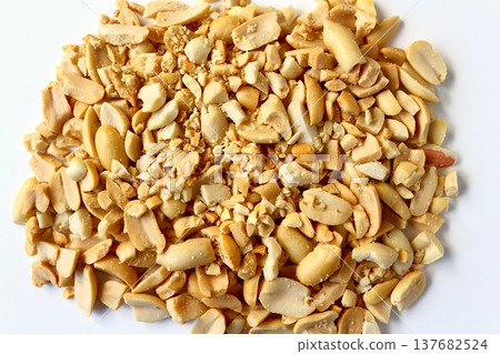 Crushed peanuts against a white background, viewed from directly above. Crushed peanuts against a white background, viewed from directly above. 137682524