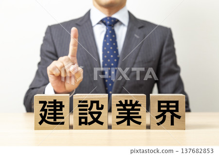 A block with the words "Construction Industry" written on it and a businessman A block with the words "Construction Industry" written on it and a businessman 137682853