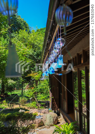 Cool glass wind chimes hanging from the eaves of a traditional Japanese building. 137683040
