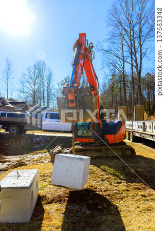 Excavator lifts heavy object from ground on construction site 137683348