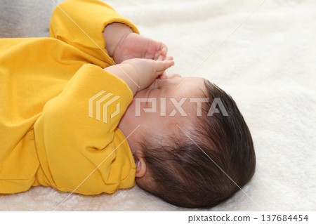 A sleepy baby rubbing its eyes A sleepy baby rubbing its eyes 137684454