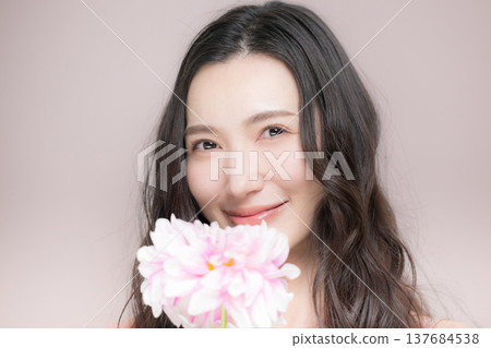 一位女子手持大麗花,散發著幸福、春意盎然的粉紅色光芒,在美麗的畫面中直視鏡頭。 一位女子手持大麗花,散發著幸福、春意盎然的粉紅色光芒,在美麗的畫面中直視鏡頭。 137684538