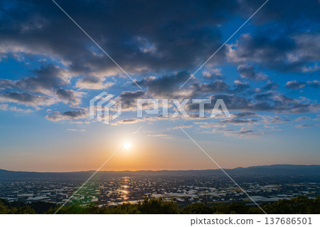 [A magnificent view in early summer] Sunset in the Tonami Plain and scattered villages in early summer and reflections in the rice fields [Toyama Prefecture] 137686501