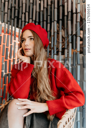 Woman Beret Fashion Young woman in a red beret and sweater sits pensively against a decorative beaded curtain background 137686654