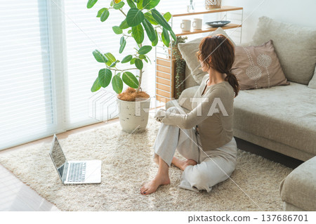 A woman doing yoga in her living room while watching a video. A woman doing yoga in her living room while watching a video. 137686701