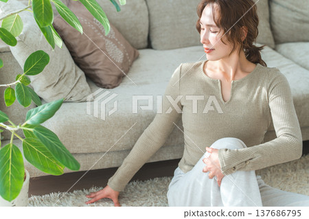 一位女士在家裡的客廳做伸展運動和柔軟度練習。 137686795