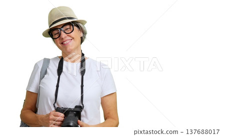 Smiling mature woman traveling, holding camera, wearing hat Smiling mature woman traveling, holding camera, wearing hat 137688017