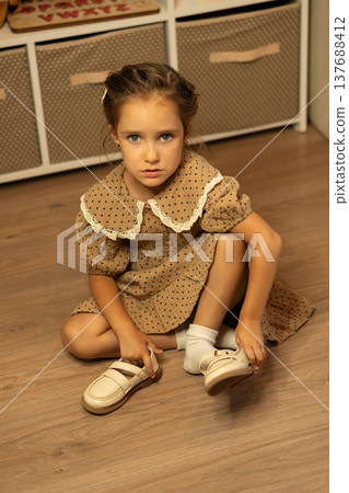 Little Girl Sitting On Floor Putting On Shoes Little Girl Sitting On Floor Putting On Shoes 137688412