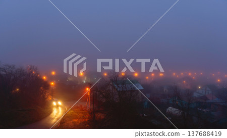 Foggy Night Street With Car Headlights And Streetlights Foggy Night Street With Car Headlights And Streetlights 137688419