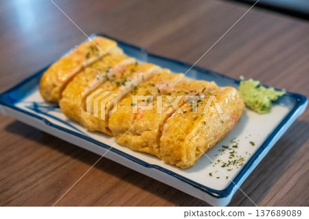 Tamagoyaki, a Japanese omelette made by rolling together several layers of fried beaten eggs, served on a plate. Tamagoyaki, a Japanese omelette made by rolling together several layers of fried beaten eggs, served on a plate. 137689089
