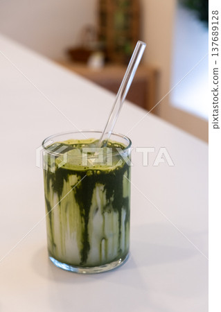 A glass of iced green tea latte, on the white table 137689128