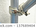 Metal clamps (swivel clamps) for scaffolding at a construction site, secured with rusted bolts. 137689404