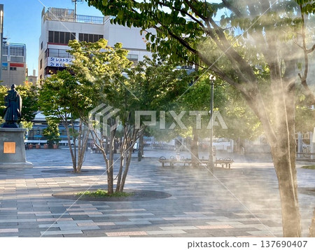 Kofu Station North Exit Plaza in summer, where mist is being released to combat the heat. (6) Kofu Station North Exit Plaza in summer, where mist is being released to combat the heat. (6) 137690407
