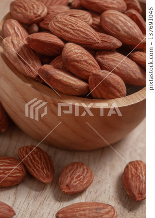 Almonds placed in a wooden cup and on a natural wood plate, highlighting simple organic textures. Almonds placed in a wooden cup and on a natural wood plate, highlighting simple organic textures. 137691046