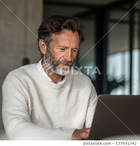 Professional man focused on laptop in modern workspace showcasing productivity and technology use for work from home or office setup in contemporary environment. Generative AI 137691342