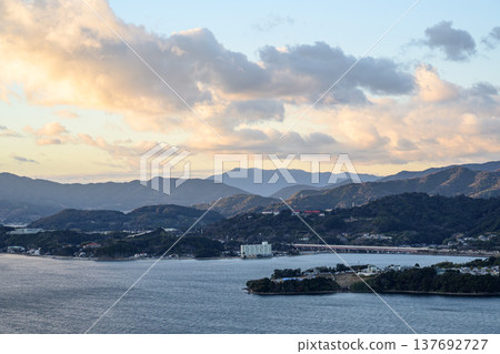 The pre-sunset scenery of the mountains and townscape stretching out beyond the lake. The pre-sunset scenery of the mountains and townscape stretching out beyond the lake. 137692727