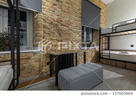 Industrial Hostel Dormitory with Bunk Beds and Brick Wall 137693669