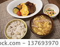 Omelet hamburger steak with demi-glace sauce and deep-fried vegetables, served as a set meal. 137693970