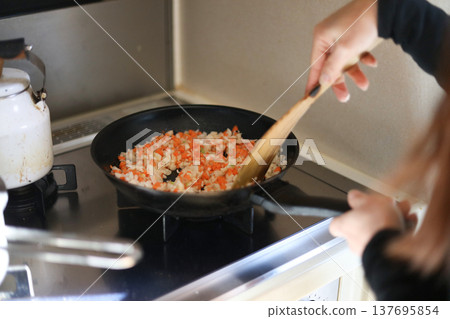 Woman frying chopped vegetables Woman frying chopped vegetables 137695854