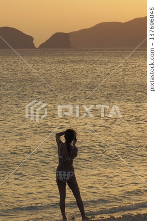 日落時分，一位身著比基尼的女子在海中嬉戲－沖繩美景 137696048