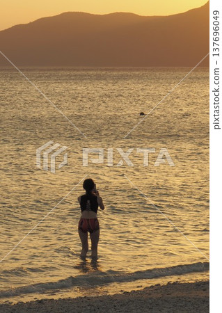 日落時分，一位身著比基尼的女子在海中嬉戲－沖繩美景 137696049