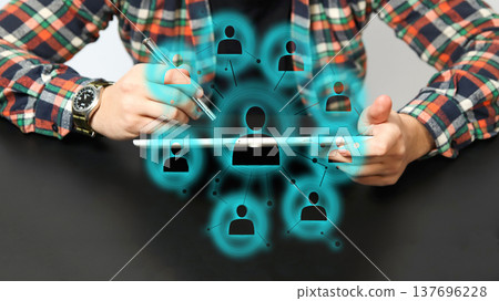 Futuristic human resources and social network concept. Businessman using tablet with glowing digital interface showing interconnected people icons. Global recruitment and team management technology 137696228