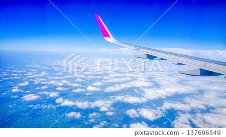 Plane wing glides above fluffy white clouds 137696549