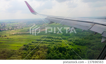 Airplane wing extends over lush green fields Airplane wing extends over lush green fields 137696563